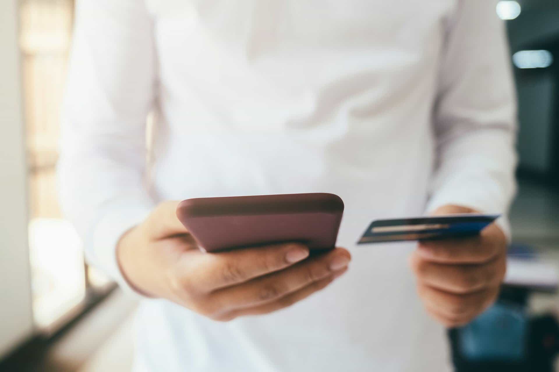 Hands holding a credit card and a phone.